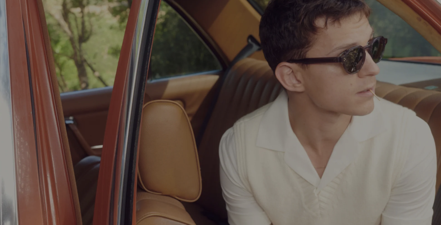 Tom sitting inside a vintage car wearing sunglasses and a light-colored shirt.