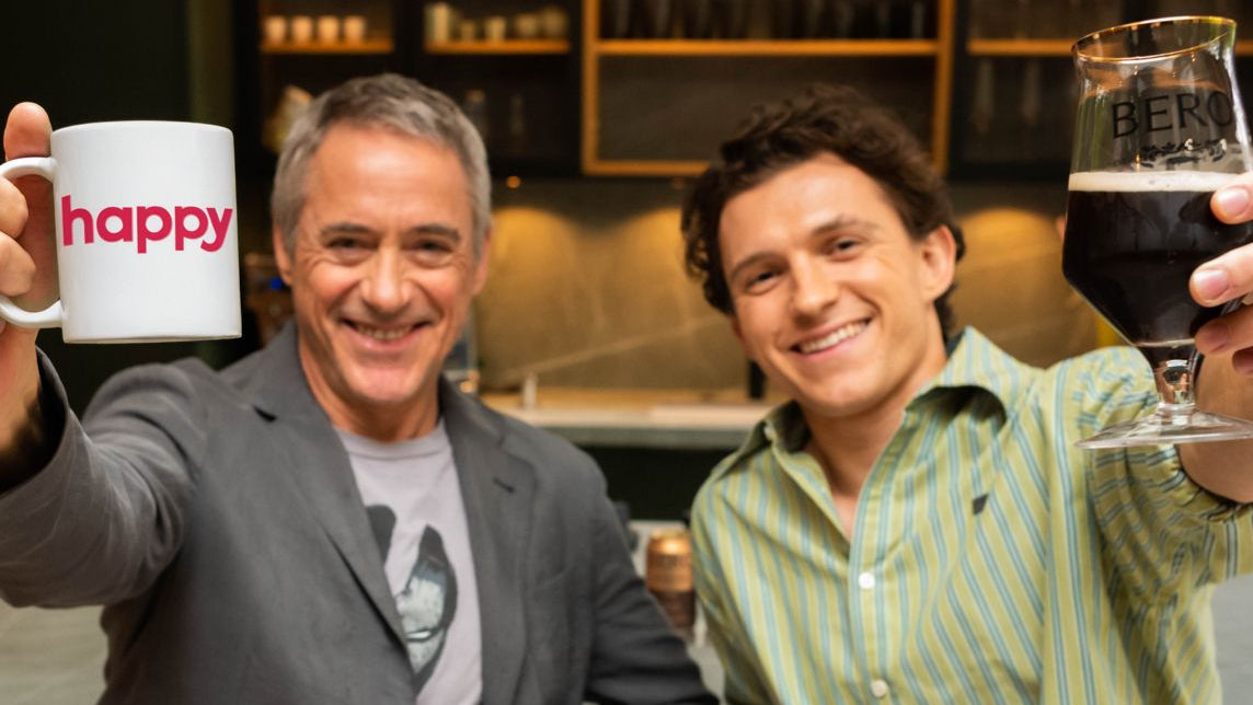 Robert Downey, Jr. holding a mug with 'happy' and Tom Holland holding a glass of BERO