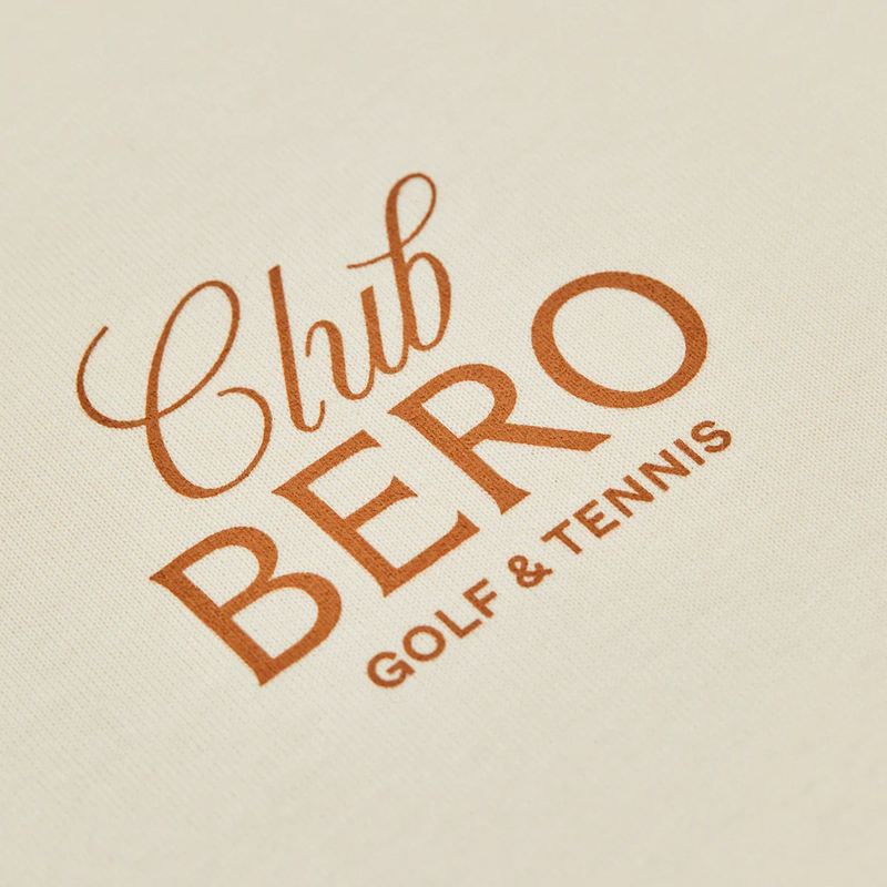 Club BERO Golf & Tennis logo embroidered in orange lettering on cream fabric
