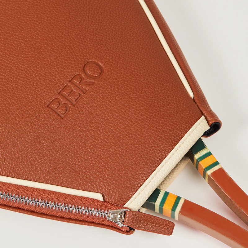 Brown leather tennis racquet cover with BERO logo embossed on surface, zipper closure visible