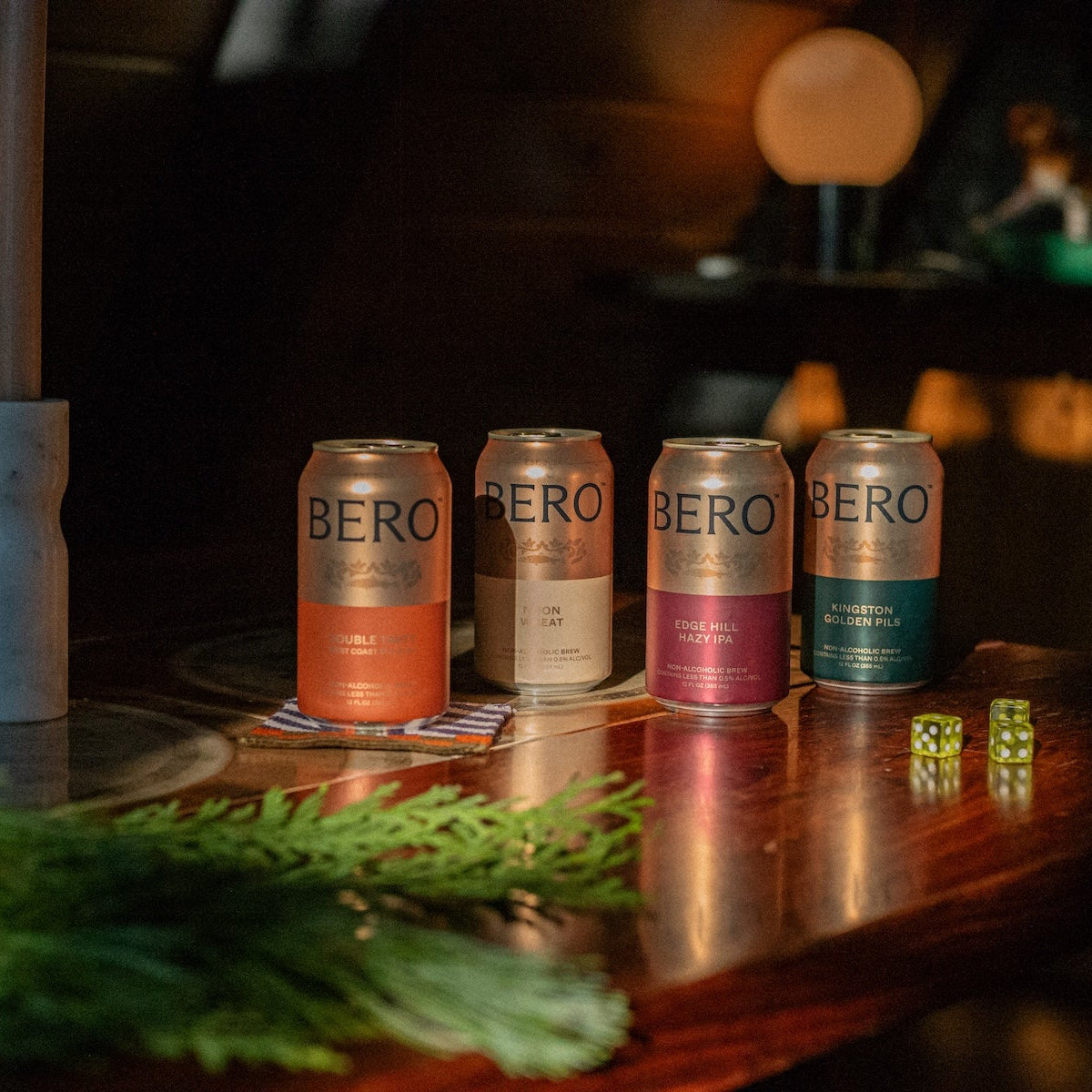 All four BERO cans on a table next to some dice