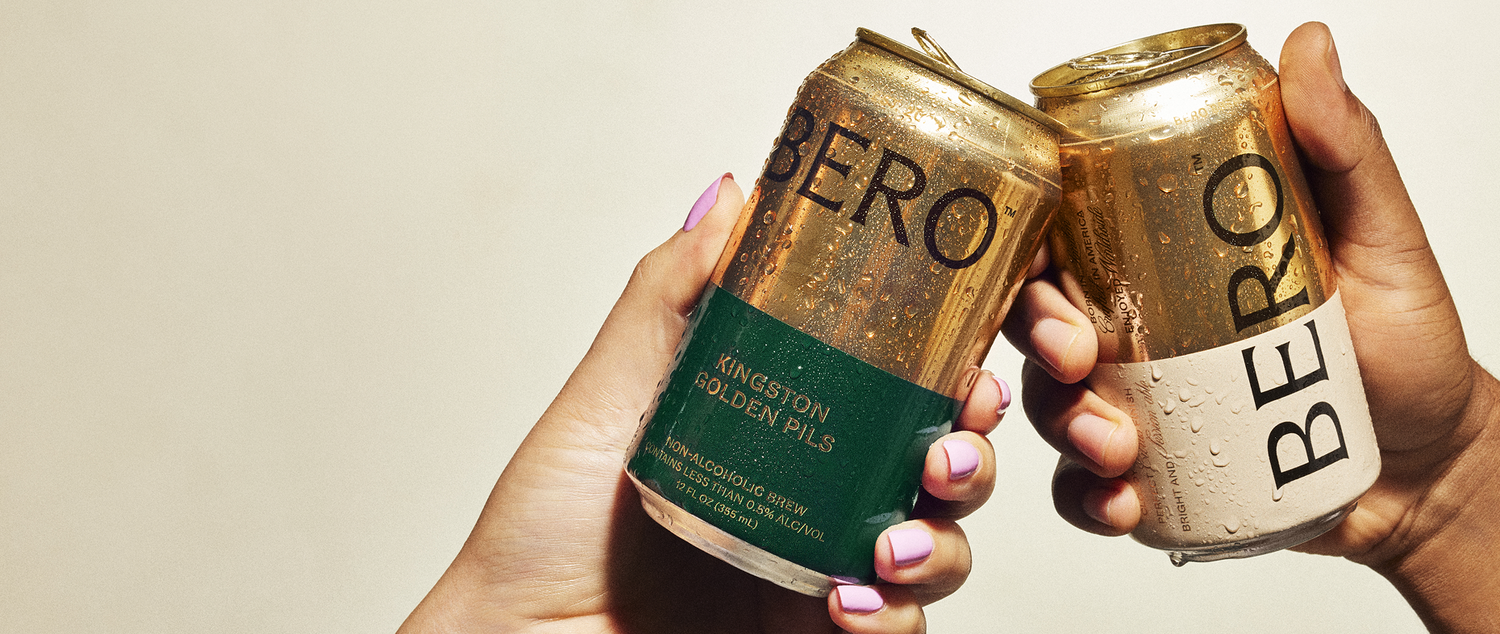 Two hands cheersing cans of Kingston Golden Pils and Noon Wheat