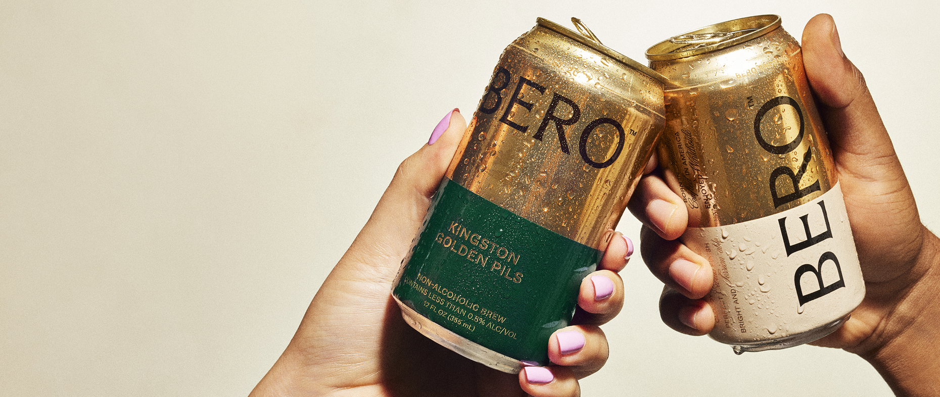 Two hands cheersing cans of Kingston Golden Pils and Noon Wheat