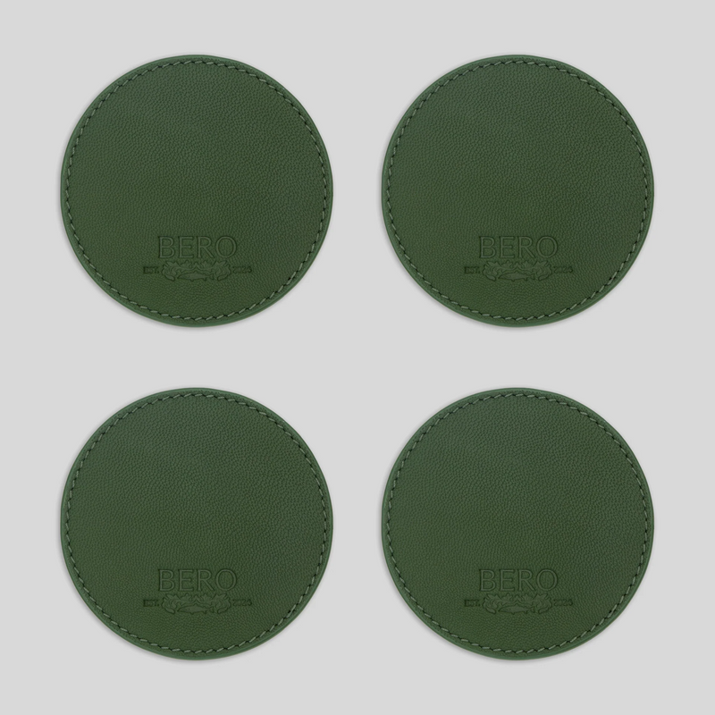 Four green leather coasters with embossed BERO logos arranged in a 2x2 grid on white background