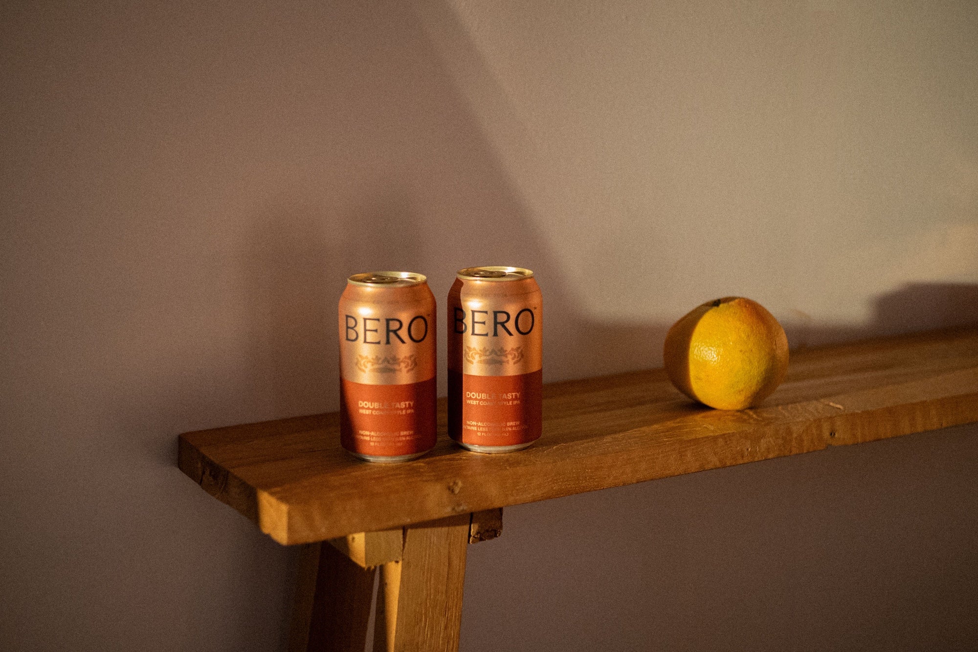 Two cans of Bero on a wooden surface with a grapefruit beside them 
