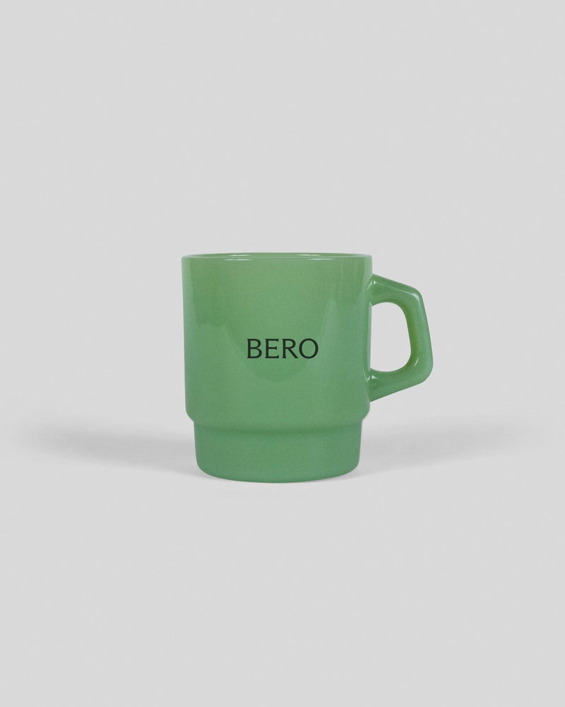 Green ceramic mug with "BERO" text printed in black letters, featuring a stackable design with rounded handle
