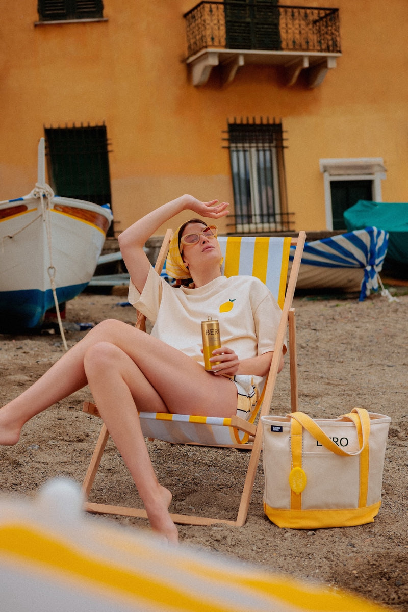 Woman on a beach chair wearing the BERO Shandy t-shirt drinking a Shandy