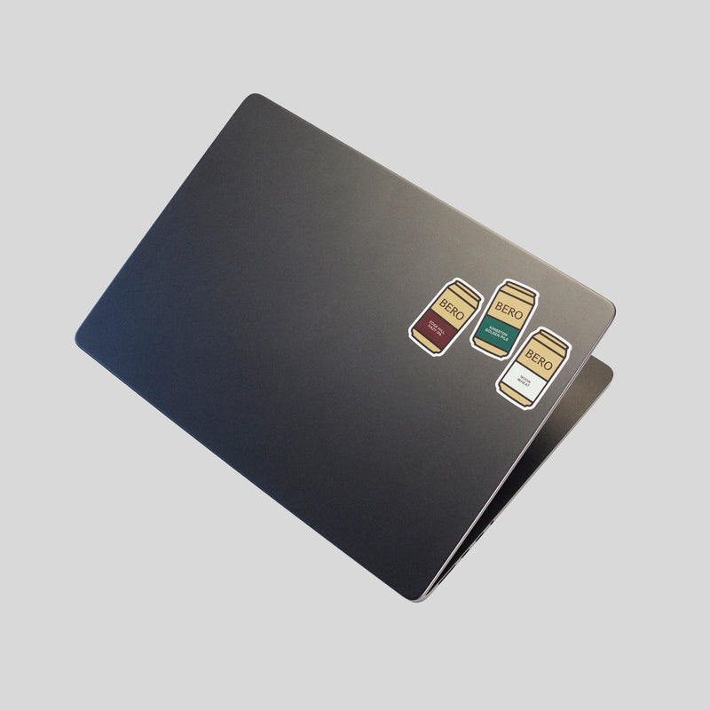 Laptop with three BERO non-alcoholic beer can stickers in different colors arranged on the back cover