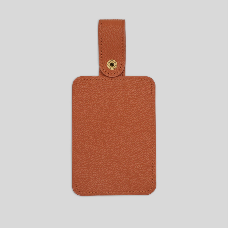 Brown leather golf tee holder with snap closure and stitched edges against light gray background