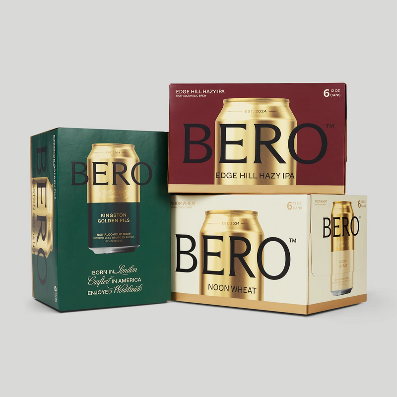 Three BERO non-alcoholic beer 6-packs: Kingston Golden Pils in green packaging, Edge Hill Hazy IPA in red, and Noon Wheat in cream packaging